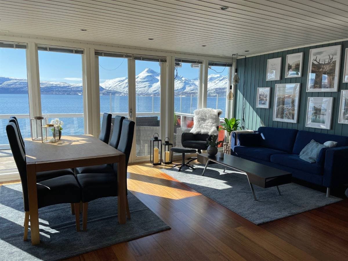 Stue og spiseplads med udsigt over fjorden og fjeldene