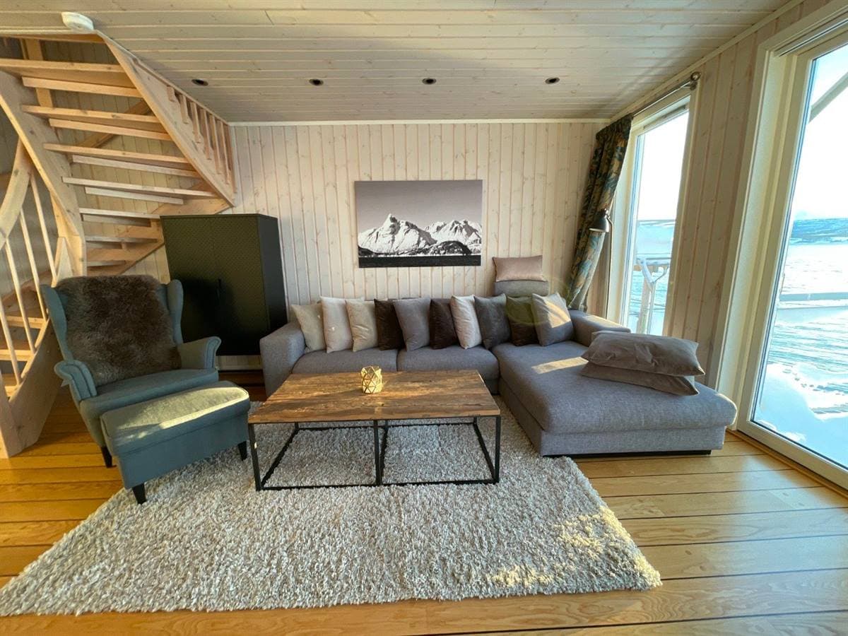 Stue med sofa, trappe og fjordudsigt