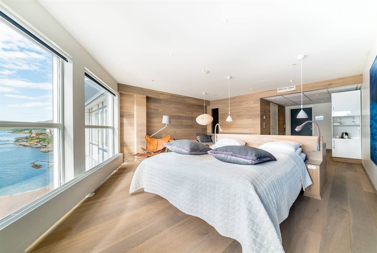 Juniorsuite med dobbeltseng, siddeområde og store vinduer ud mod fjorden
