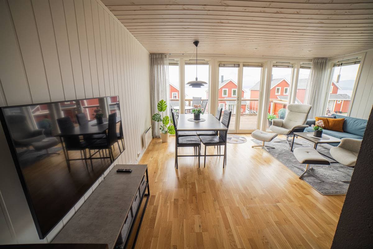 Åben stue og spiseplads med store vinduer